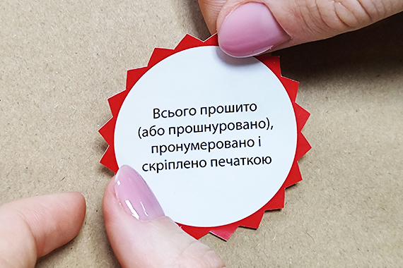 Червона наклейка нотаріуса для завірки документів після прошивки нитками